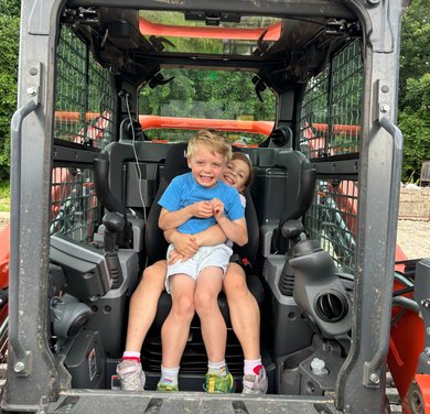 two children sitting together inside Flannel Landworks forestry equipment